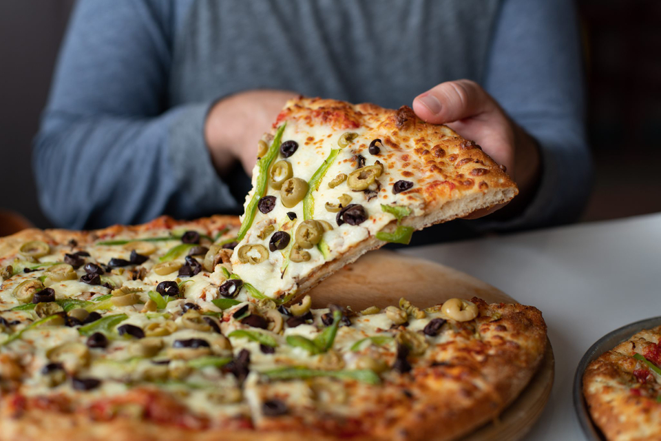 Personne tenant une tranche de pizza de luxe.